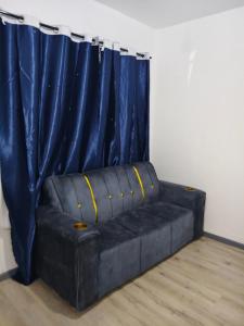 un canapé noir devant un rideau bleu dans l'établissement FairValley, à Athi River