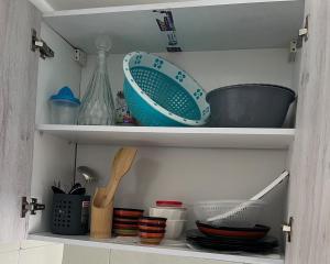 a cabinet filled with bowls and other kitchen utensils at Apartamento Familiar con Piscina en Bayt Al Bahr Asilah in Asilah