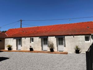a white building with a red roof with potted plants at Aux Pas Sages, 4 logements mitoyens, proche mer in Saint-Jean-de-Monts