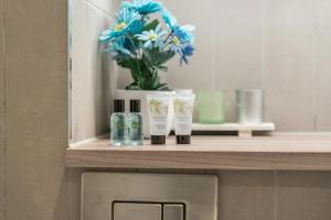 a shelf with three products on it with a vase of flowers at Luxury 3BR with 2bath Near Westfield Stratford in London +41 photos
