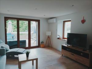 a living room with a flat screen tv and a couch at Le refuge de la source in Bussang