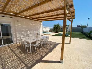 a wooden deck with a table and chairs under a wooden pergola at Villatella in Burriana