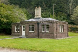 an old brick building with a chimney on the grass at Salterbridge Gatelodge in Cappoquin