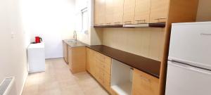 a kitchen with wooden cabinets and a white refrigerator at Thalassa View c3 in Khalkoútsion