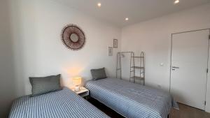 Un dormitorio con dos camas y un espejo en la pared. en Charming Baixa VI - 2 Room Apt, en Lavradio