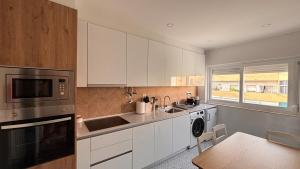 Una cocina con gabinetes blancos, un fregadero y un microondas. en Charming Baixa VI - 2 Room Apt, en Lavradio