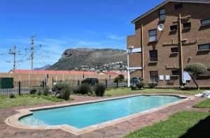a swimming pool in front of a building at Stylish beachside Gem in Fish Hoek in Fish Hoek