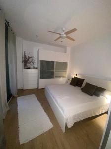 a bedroom with a white bed and a ceiling fan at Casa grande y céntrica con piscina en zona peatonal in Montgat