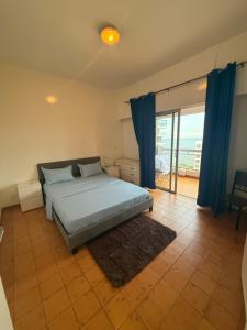 a bedroom with a bed with blue curtains and a balcony at Appartement F3 avec vue imprenable sur la mer, Dakar - Plateau in Dakar