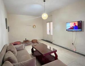 a living room with a couch and a tv on the wall at Appartement Spacieux pour Famille Mâarif Casablanca in Maarif