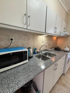 a kitchen with a microwave and a sink at Departamento centrico Avenida Cordoba Edificio Campanarios XIX in Esperanza +2 photos