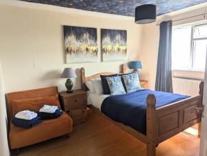 un dormitorio con una cama y una silla en Central Pembrokeshire family home pets welcome 7 guests, en Neyland