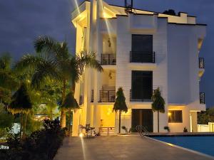 a white building with a swimming pool in front of it at Nakupenda Afrika near JNIA Airport in Kisarawe