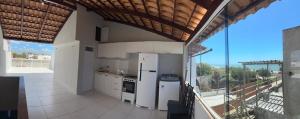 a large kitchen with white appliances and a balcony at Suítes House Cacique in Cruz