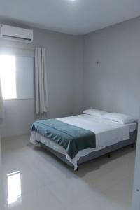 a bedroom with a bed in a white room at Suítes House Cacique in Cruz