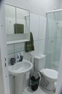 a white bathroom with a toilet and a sink at Suítes House Cacique in Cruz