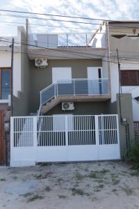 a white fence in front of a house at Suítes House Cacique in Cruz