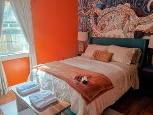 a bedroom with a bed with an orange wall at Winter Escape Pet Friendly Cottage with Jacuzzi Tub and Reading Nook in Pensacola