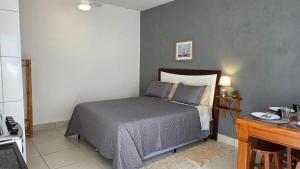 a small bedroom with a bed and a desk at Kitnet 3 próxima da USP, CPO e Centrinho HRAC in Bauru