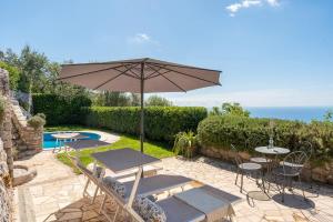 a patio with an umbrella and tables and a pool at Villa Esposito in Massa Lubrense