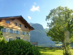 Ein Gebäude auf einem Feld mit einem Baum daneben. in der Unterkunft Ferienwohnung Bauernhaus Untermoas in Abtenau