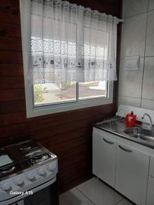 a kitchen with a window and a stove and a sink at Vilamar in Florianópolis +1 photo