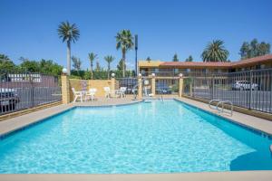a swimming pool at a resort with blue water at Hotel Seville - Ontario Airport/Chino in Ontario