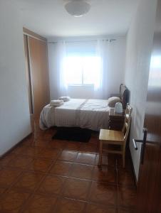 a bedroom with a bed and a table and a window at Apartamento T2 Vista mar in Vila do Conde