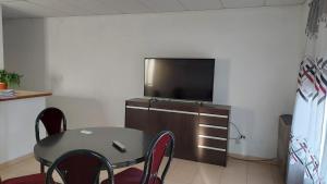 Una sala de estar con una mesa y un televisor en una pared. en El Cacique, en General San MartÃ­n