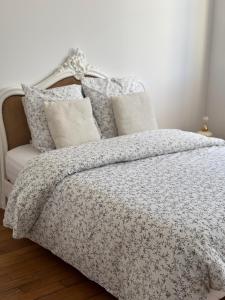 a bedroom with a bed with a gray and white comforter at La Petite Parisienne-Centre ville -Gare -Airport in Beauvais