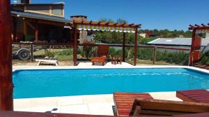a swimming pool with a pergola and a house at Cabañas Mi Capricho in Santa Rosa de Calamuchita +4 photos