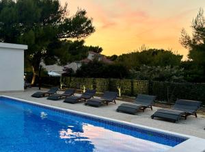 a row of lounge chairs next to a swimming pool at White Villa, Brac in Splitska