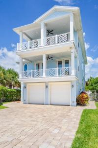 a large white house with two garage doors at Heated Pool Elevator Game Room & Ocean Decks in Coquina Gables
