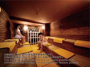 two men sitting in a sauna with a man sitting at Shinjuku Kuyakusho-mae Capsule Hotel in Tokyo