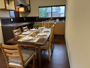 a dining room table with chairs and a kitchen at Thistle Lodge in Myoko