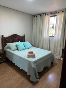 サン・ジョアン・デル・レイにあるApartamento confortável e espaçosoの青い枕と窓のあるベッドのある寝室