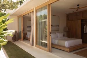 a bedroom with a bed and sliding glass doors at COZ Bali Boutique Villas walking distance to Padang Padang Beach in Uluwatu +146 photos
