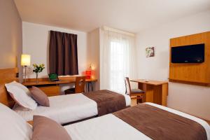 ラ・ロシェルにあるSéjours & Affaires La Rochelle Les Minimesのベッド2台とデスクが備わるホテルルームです。