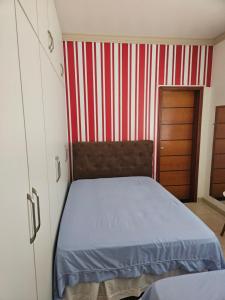 a bedroom with a bed and a red and white striped wall at Apartamento no centro in Primavera do Leste