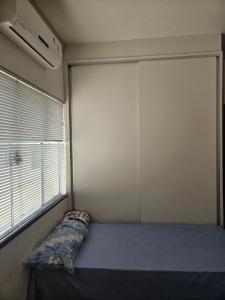 a bedroom with a blue bed and a window at Apartamento no centro in Primavera do Leste