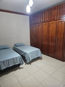 a bedroom with two beds and wooden cabinets at Apartamento no centro in Primavera do Leste