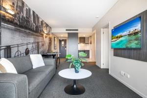 a living room with a couch and a tv on a wall at Spacious Apartment in Heart of Southbank in Melbourne
