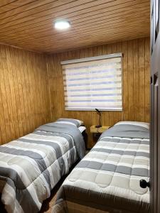 two beds in a room with a window at Cabañas Rivera Del Ancoa in Linares