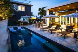 La Victoria King Suite - Kitchen Resort Vibe Near Beach في سان خوان: مسبح مع كراسي ومظلات بجوار منزل