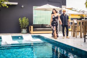 La Victoria King Suite - Kitchen Resort Vibe Near Beach في سان خوان: رجل وامرأه واقفين بجانب مسبح