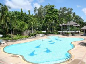 a pool at a resort with trees in the background at The Golf Lodge Hotel Laem Chabang Golf in Ban Nong Wa