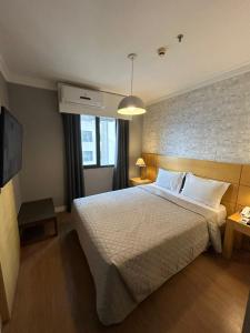 a bedroom with a large bed and a brick wall at Hotel Aeroporto Congonhas com cozinha e sacada 1108 S in Sao Paulo +40 photos
