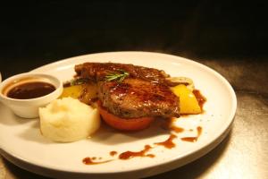 a plate of food with meat and potatoes and sauce at Wai Ora Lakeside Spa Resort in Rotorua
