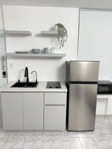 a white kitchen with a refrigerator and a sink at sleep & go apartment in Las Piedras