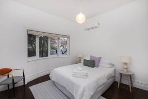 une chambre blanche avec un lit et une fenêtre dans l'établissement Modern 3BR Home - 20 Mins to Melbourne CBD, à Maribyrnong